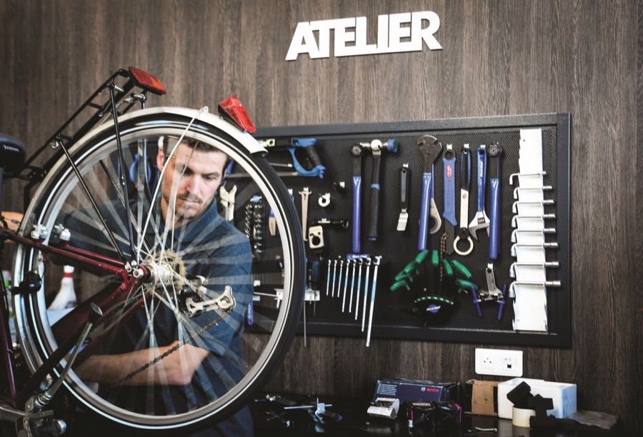 Mécanicien réparant une roue de vélo dans l'atelier Colombes Cycles